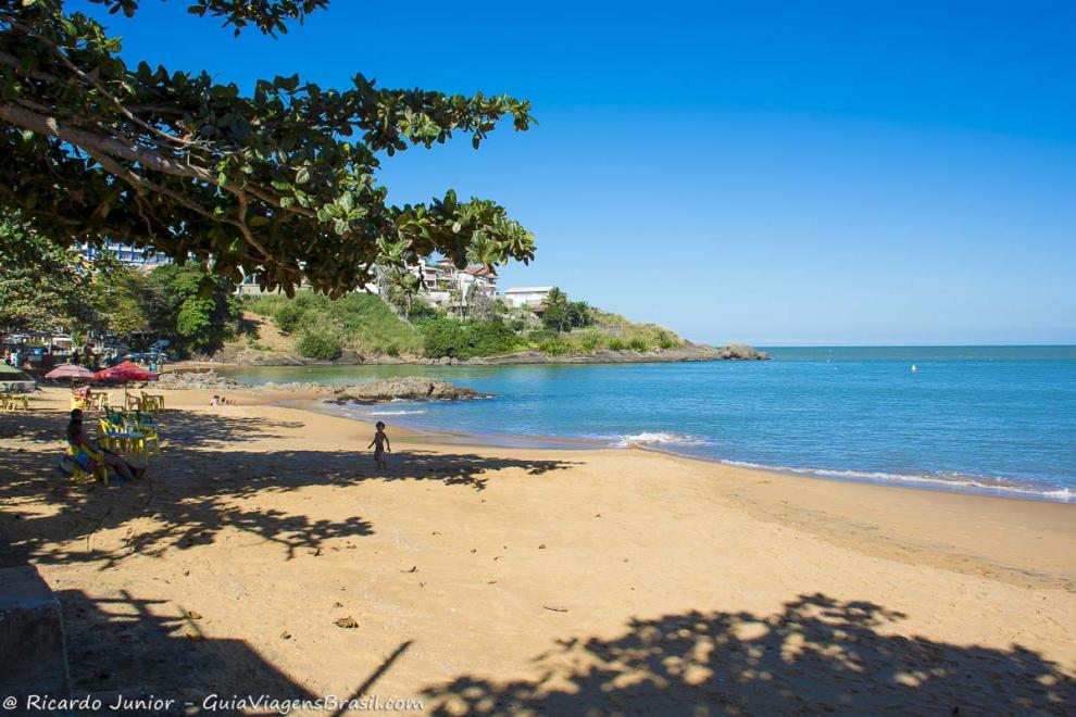 Imagem de um menino andando em direção a família na areia.